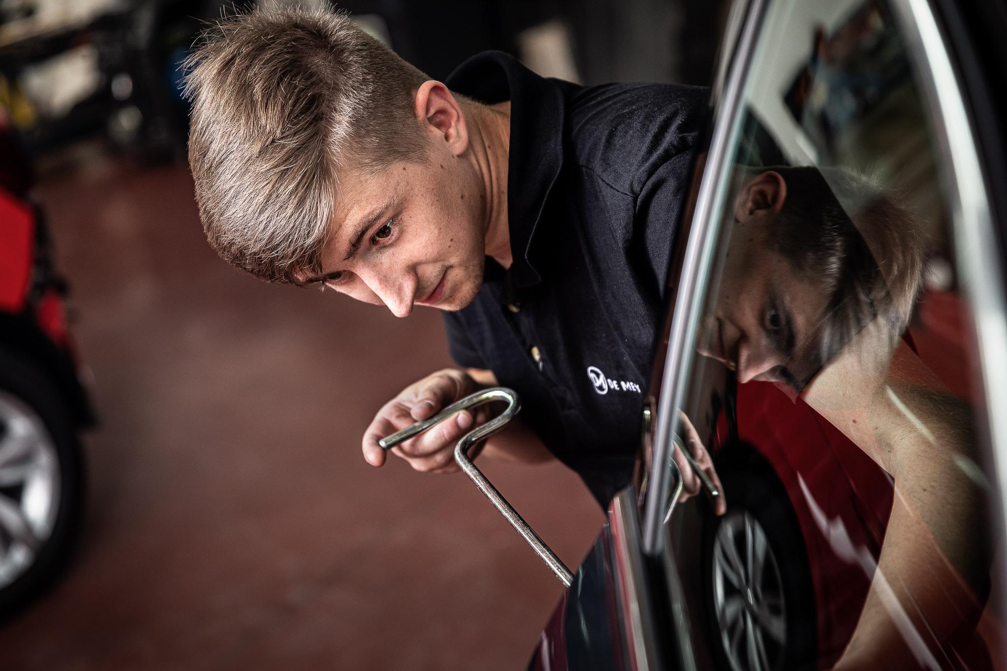 Medewerker van garage De Mey die een wagen uitdeukt